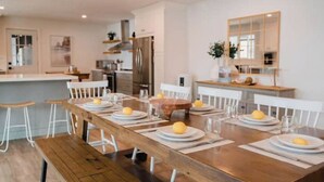 A modern kitchen with a wooden dining table set for four, equipped with white plates and glasses, and a large mirror above the table. - Beautiful 5bedroom waterfront cottage with Hot Tub (South River)