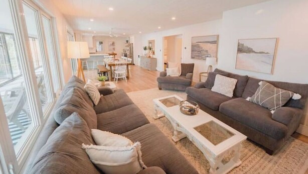 A spacious living room with a large sectional sofa, a coffee table, and a dining area in the background. - Beautiful 5bedroom waterfront cottage with Hot Tub (South River)