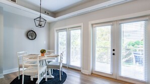 A dining area with a round table, white chairs, a black rug, and a wall clock.