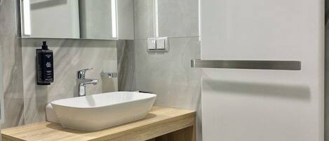 A modern bathroom with a white sink, mirror, and cabinet.