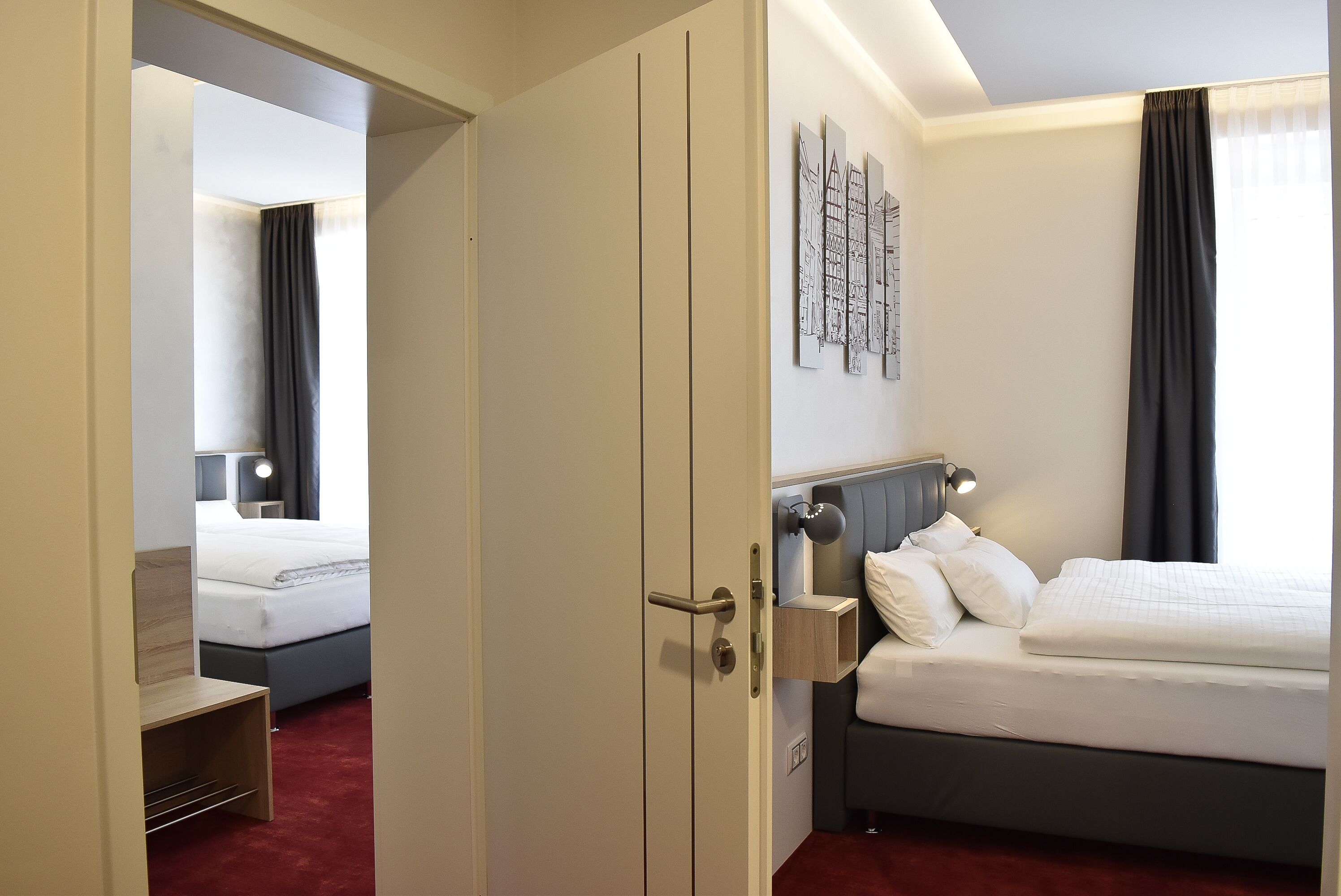 Quarto de hotel com cama, mesa de cabeceira, luminária e obra de arte na parede.
