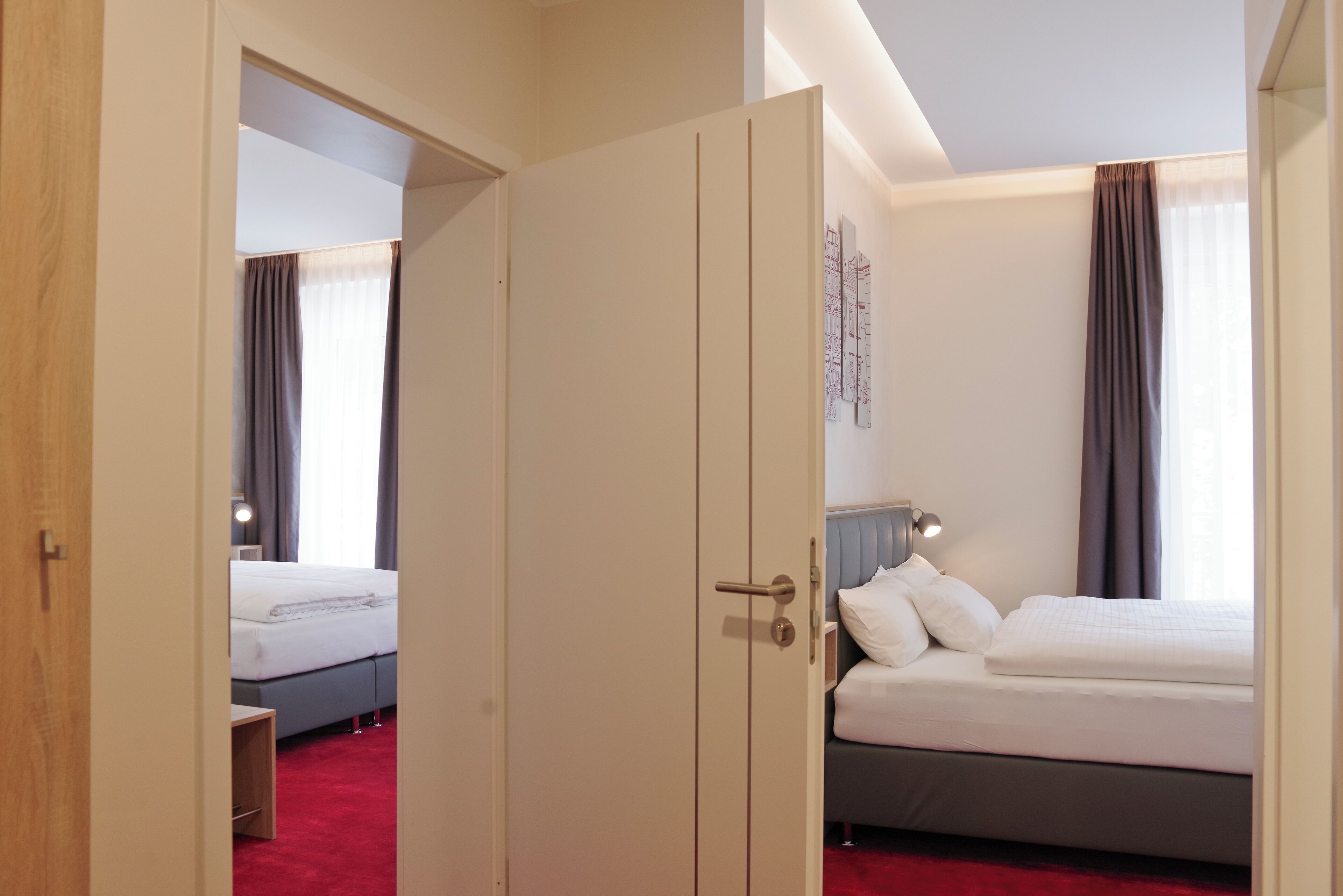A hotel room with a large bed, a bedside table, a lamp, and a wardrobe.