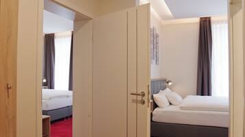 A hotel room with a large bed, a bedside table, a lamp, and a wardrobe.