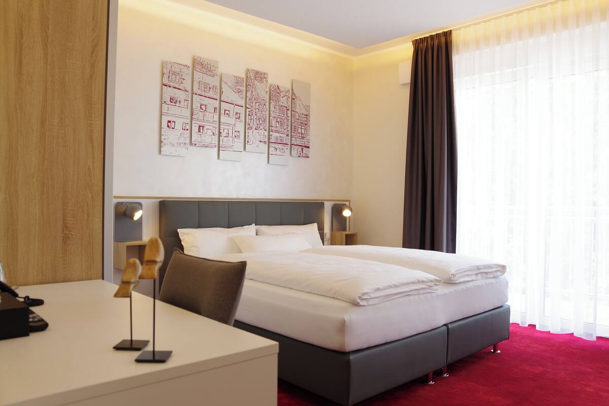Een hotelkamer met een groot bed, een bureau met stoel, en kunst aan de wand.