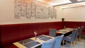 Een restaurant met rode banquettes en tafels, elk met een placemat en bestek.