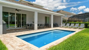 Une maison moderne dotée d’une piscine, d’un patio couvert et d’une pelouse bien entretenue.