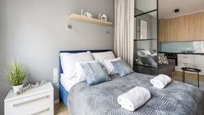 Une chambre à coucher moderne avec un lit, une table de chevet et un petit coin cuisine.