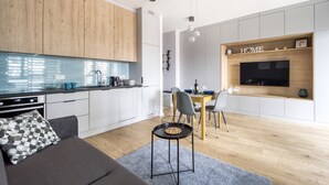 Une cuisine moderne avec des meubles blancs, un plan de travail en bois et un téléviseur encastré au-dessus de la table à manger.