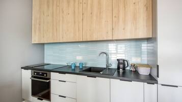 A modern kitchen with wooden cabinets, a black countertop, a sink, and a built-in oven.