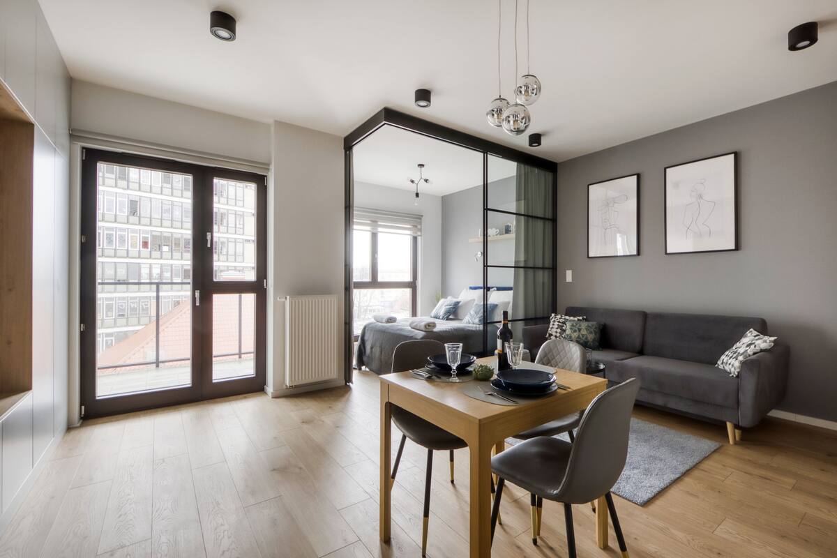 A modern living room with a dining area, large windows, and a view of the city.