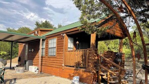 A rustic cabin with a covered porch, a small deck, and a stone patio. - Quiet cabin on the Brazos
 (Graham)