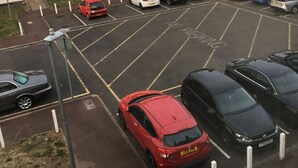 A parking lot with multiple cars, a building with a brick facade, and a clear sky. - Beautiful 2-bed Apartment in Dagenham (Dagenham)