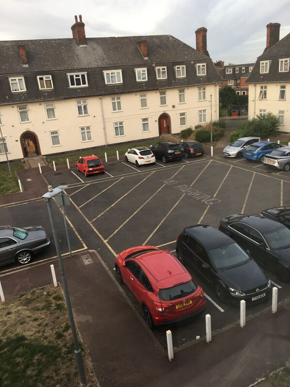 Un estacionamiento con varios coches, un edificio de ladrillo y cielo despejado.