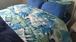 A bed with a floral bedspread and blue pillows. - Beautiful 2-bed Apartment in Dagenham (Dagenham)