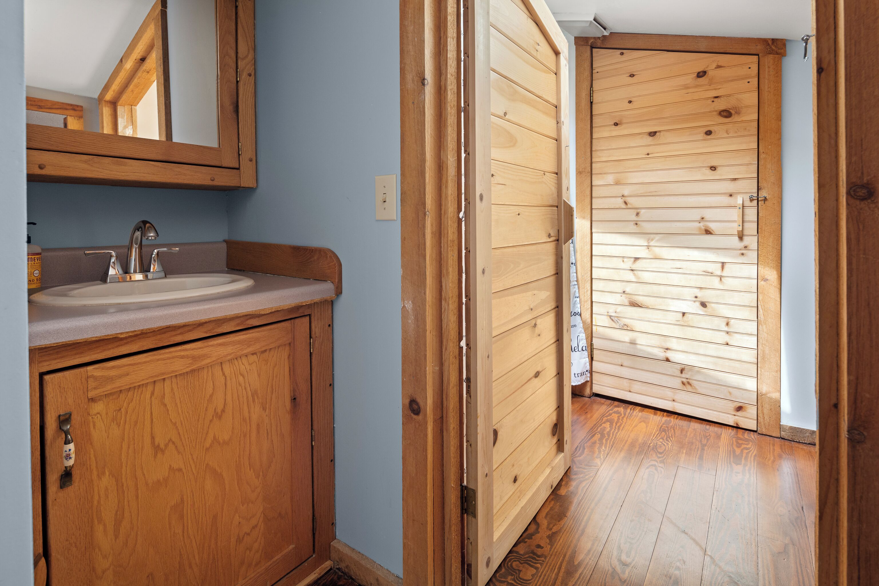 A wooden bathroom with a sink and mirror.