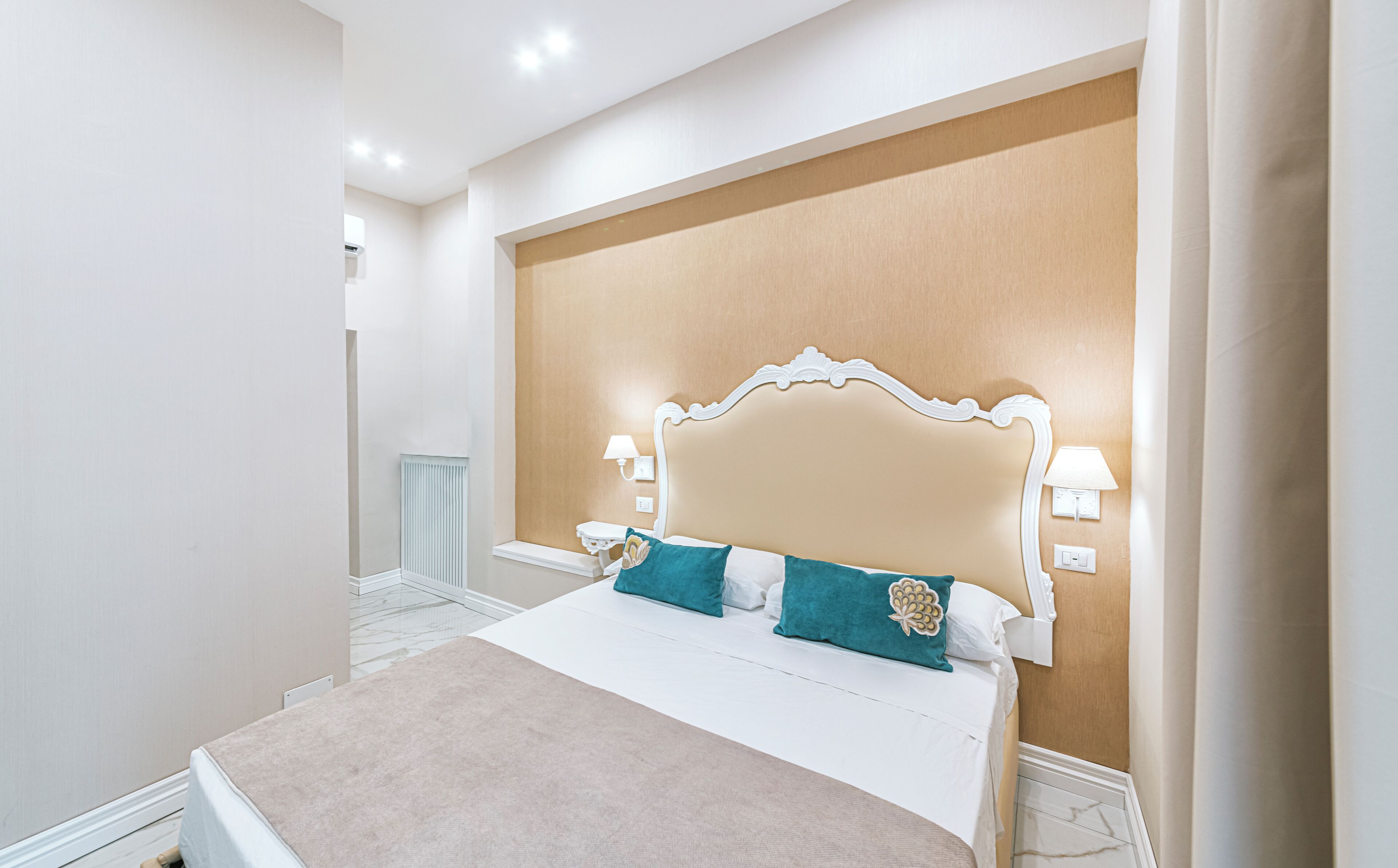A neatly arranged bedroom with a large bed, two bedside lamps, and a wall-mounted radiator.
