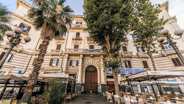A historic building with a central entrance, outdoor seating, and palm trees. - GENTILE SUITE & SPA VOMERO (Naples)
