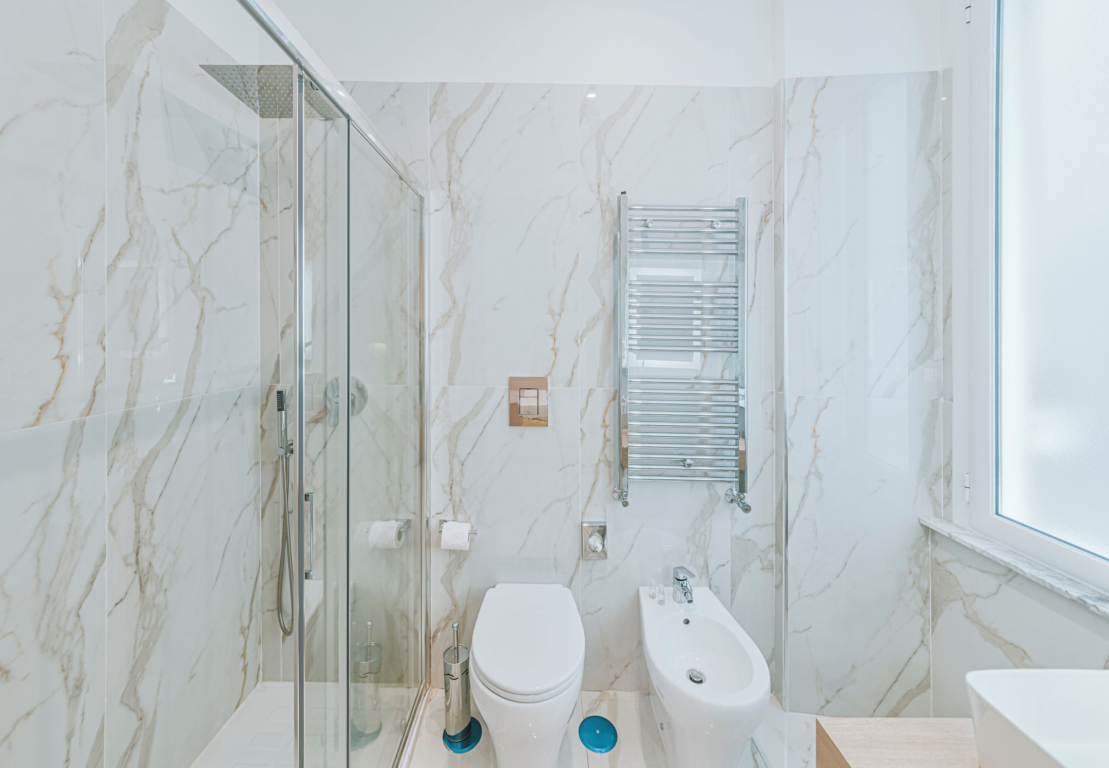 A modern bathroom with a glass shower enclosure, a toilet, a bidet, and a sink.