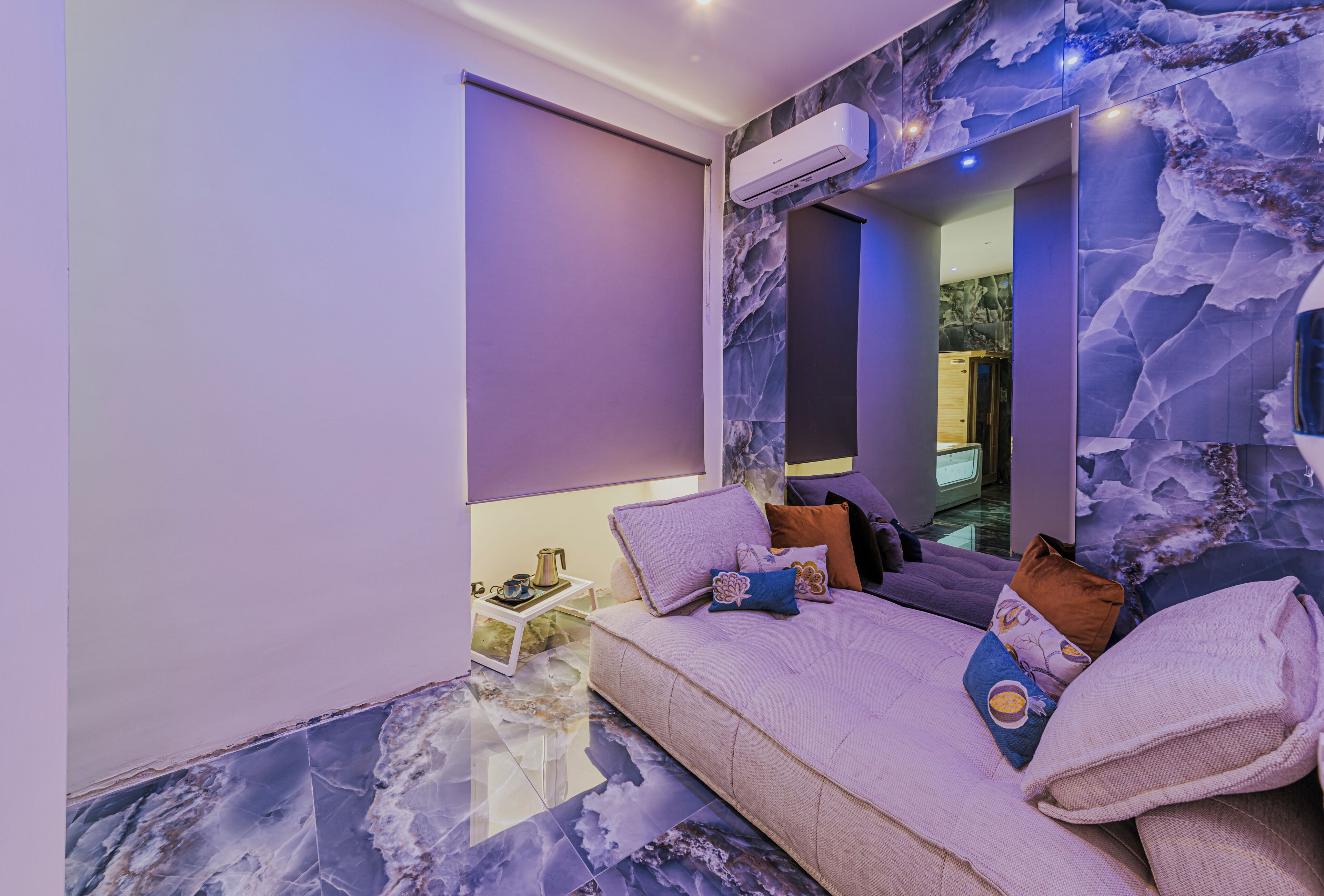 Une chambre moderne avec un sol en marbre, un canapé-lit et un grand miroir.