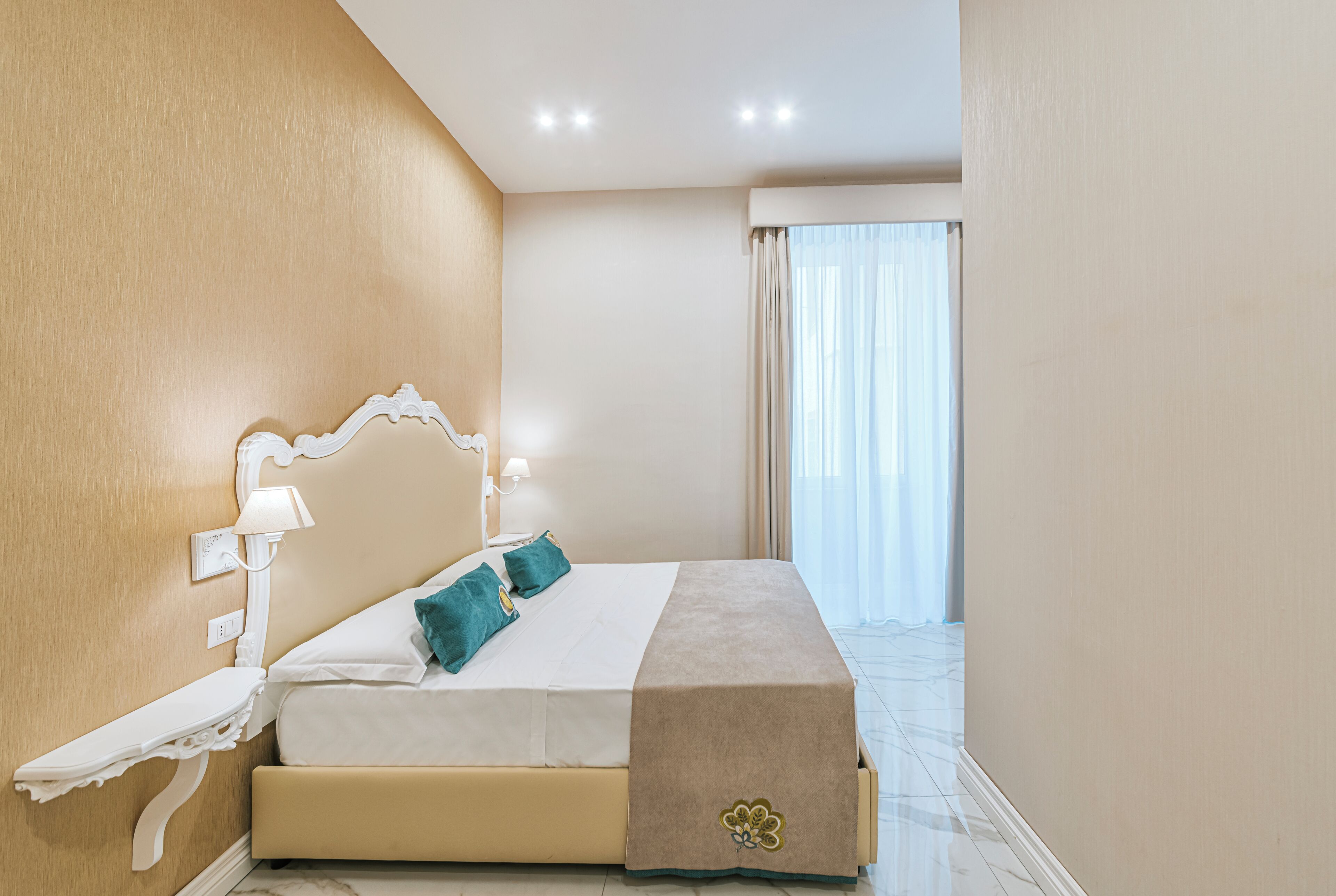 A hotel room with a bed, a nightstand, and a window with curtains.