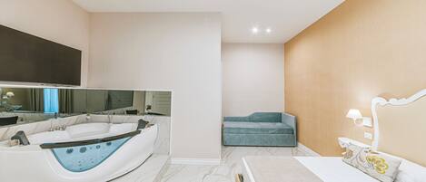 A modern bathroom with a large bathtub, a vanity with a mirror, and a separate seating area with a bench.