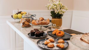 A buffet table with various pastries and desserts, including croissants, muffins, and a cake. - GENTILE SUITE & SPA VOMERO (Naples)