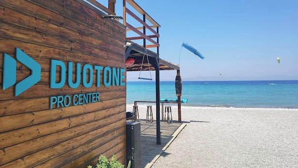 A wooden building with 'DUOTONE PRO CENTER' signage, a wooden deck, and a beach view. - Freeman Greenlees Classical Greek (Rhodes)