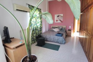 Quarto com cama, escrivaninha, planta em vaso, mesa de cabeceira e guarda-roupa.