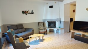 Un salon comprenant un canapé, un fauteuil, une table basse, une cheminée et un téléviseur.