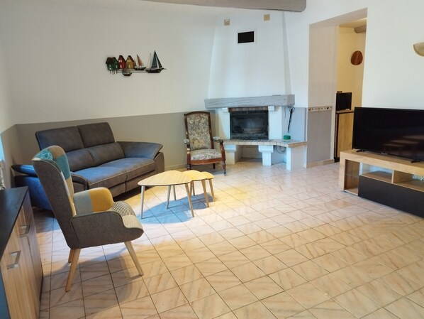 A living room with a sofa, armchair, coffee table, fireplace, and TV. - Charmante Maison en Pierres Dans Village, 200m du Canal du Midi. 30 mn Plages (Argeliers)