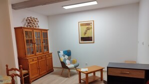 Un salon avec un meuble en bois, une chaise, une petite table et un tableau encadré au mur.