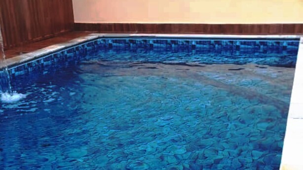 En swimmingpool med blå flisegulv og en træterrasse.