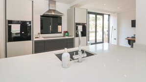 A modern kitchen with a central island, stainless steel appliances, and a large window. - Bailey House (Driffield)