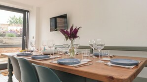A dining table set with plates, glasses, and a vase with flowers. - Bailey House (Driffield)