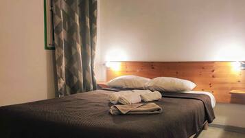 A neatly made bed with pillows and towels, a wooden headboard, and a bedside table with a lamp.