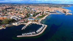 Vue aérienne d’une ville côtière avec un port de plaisance, des immeubles résidentiels et une mer d’un bleu limpide.