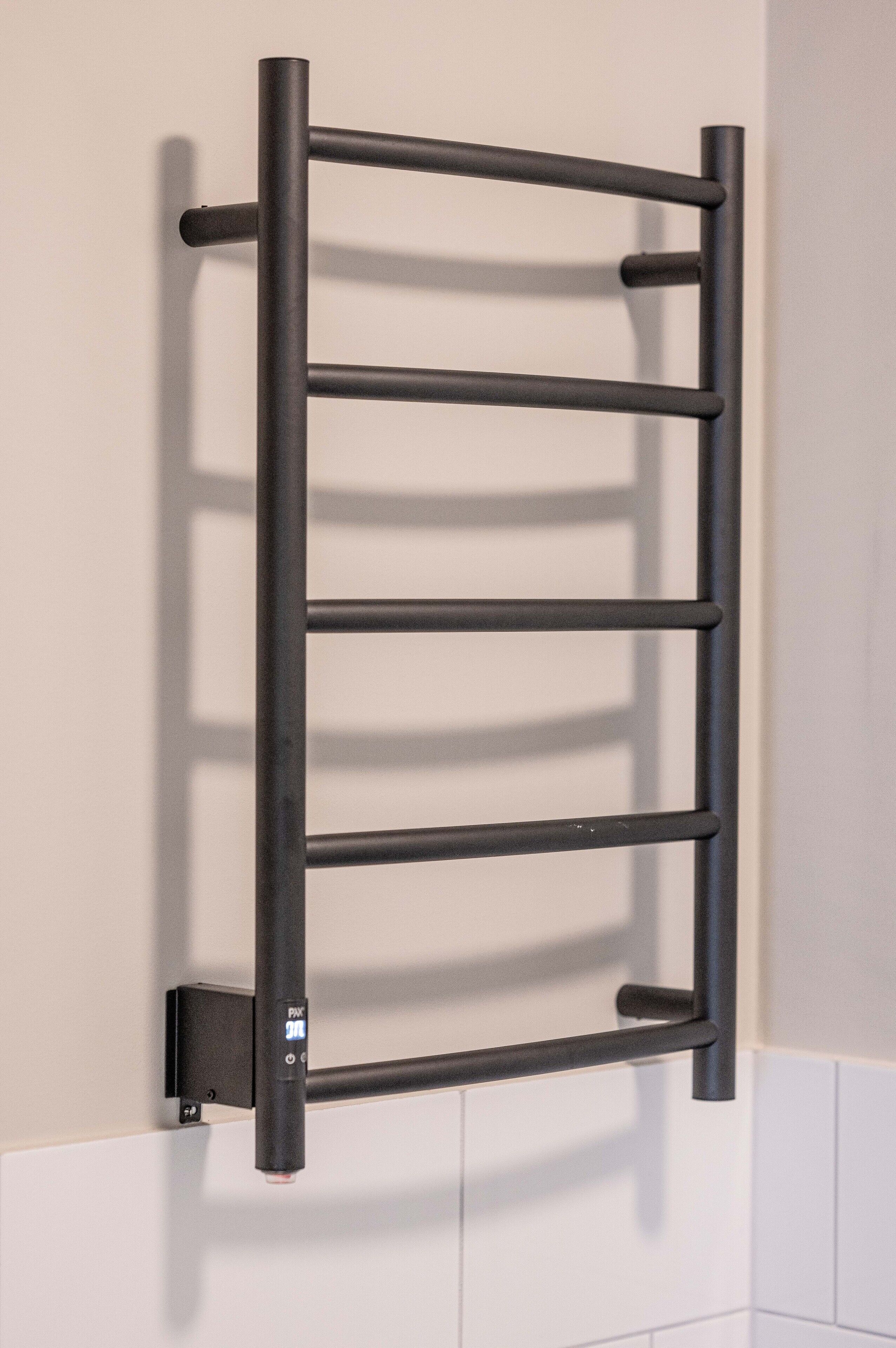 A black metal towel rack mounted on a white tiled wall.