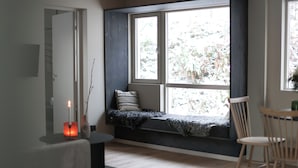 Ein Zimmer mit einer integrierten Sitzbank an einem Fenster, einem kleinen Tisch mit Kerzen und einem Stuhl.