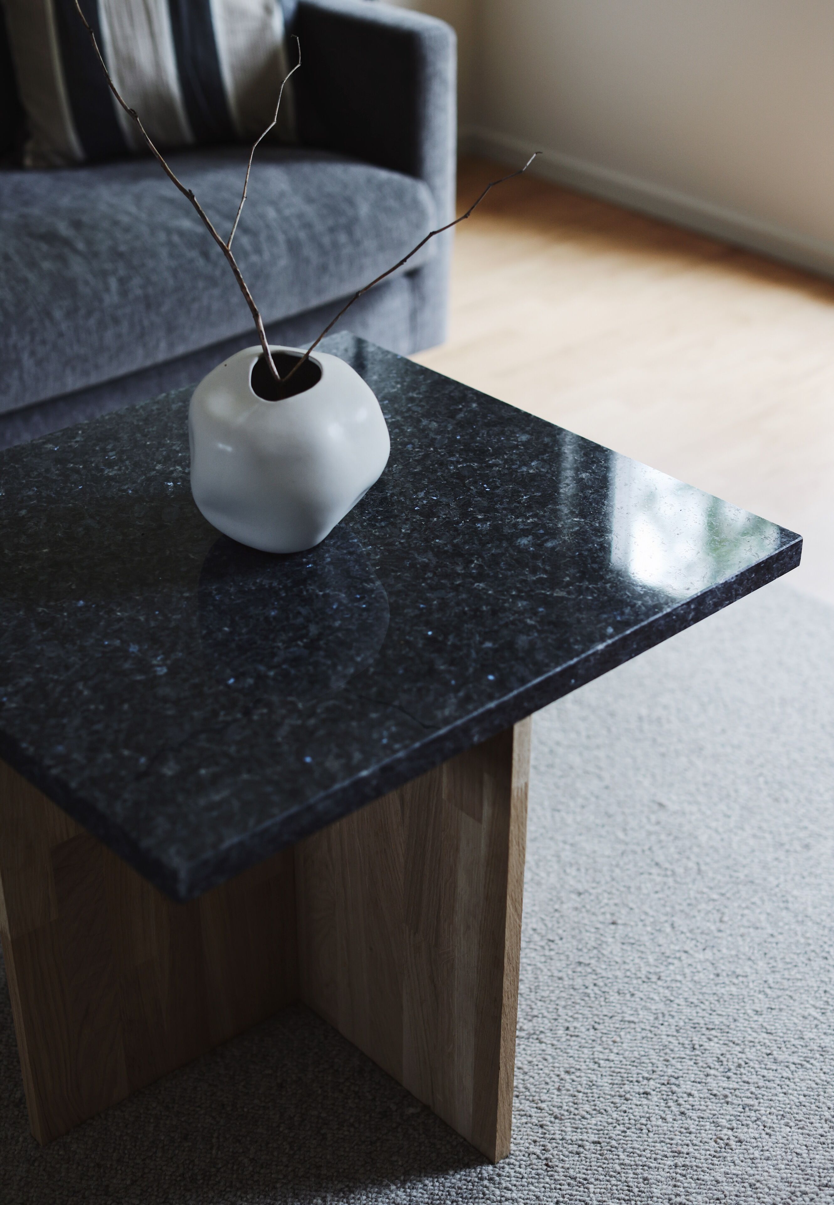 A black granite coffee table with a white vase containing branches.