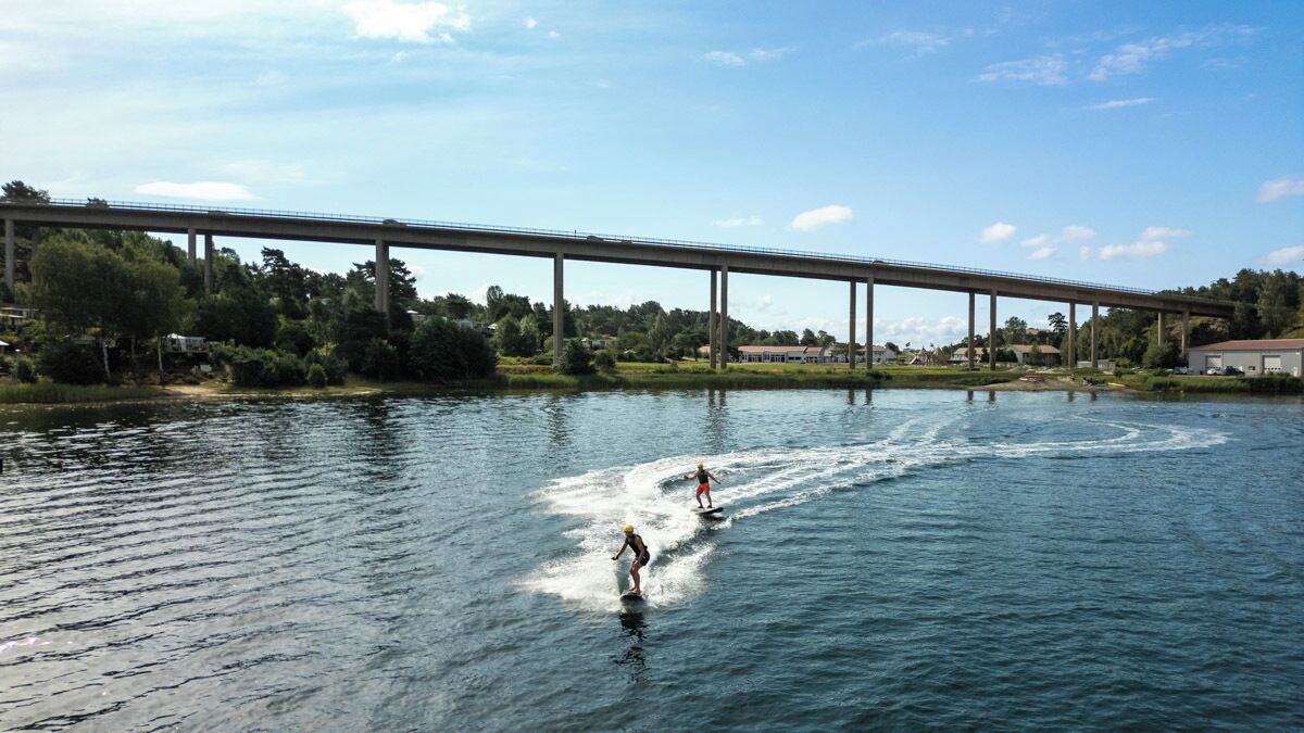Een brug over een rivier, met twee mensen die waterskiesteren.