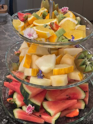 A colorful fruit platter offers a variety of fresh fruits, including orange, kiwi, melon, and pineapple.