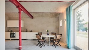 A kitchen with white cabinets, a red structural beam, and a dining area with a round table and four chairs.