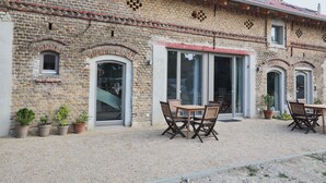 A brick building with a gravel patio, outdoor seating, and potted plants.