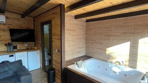 A modern cabin interior with a wooden ceiling, a kitchen area, a living room with a sofa, and a large bathtub. - Olive Garden  (Konyaalti)