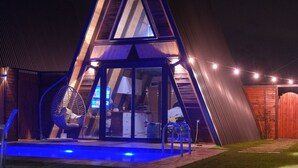 A triangular-shaped building with a glass facade, a pool, and a hanging chair. - Olive Garden  (Konyaalti)
