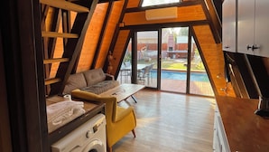A cozy, modern kitchen with wooden beams, a built-in washing machine, and a dining area with a yellow chair. - Olive Garden  (Konyaalti)