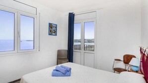 Una habitación de hotel con cama, una silla, un escritorio y vista al mar.