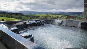 A hot tub with a view of rolling hills and a bench. - Badgers View (Rhayader)