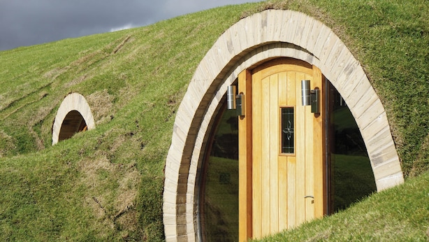 Two Hobbit-style houses with wooden doors and arched entrances, set on a grassy hill. - Badgers View (Rhayader)