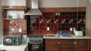 Une cuisine équipée d’un four à micro-ondes, d’une cuisinière, d’un four et d’un plan de travail recouvert de carreaux.